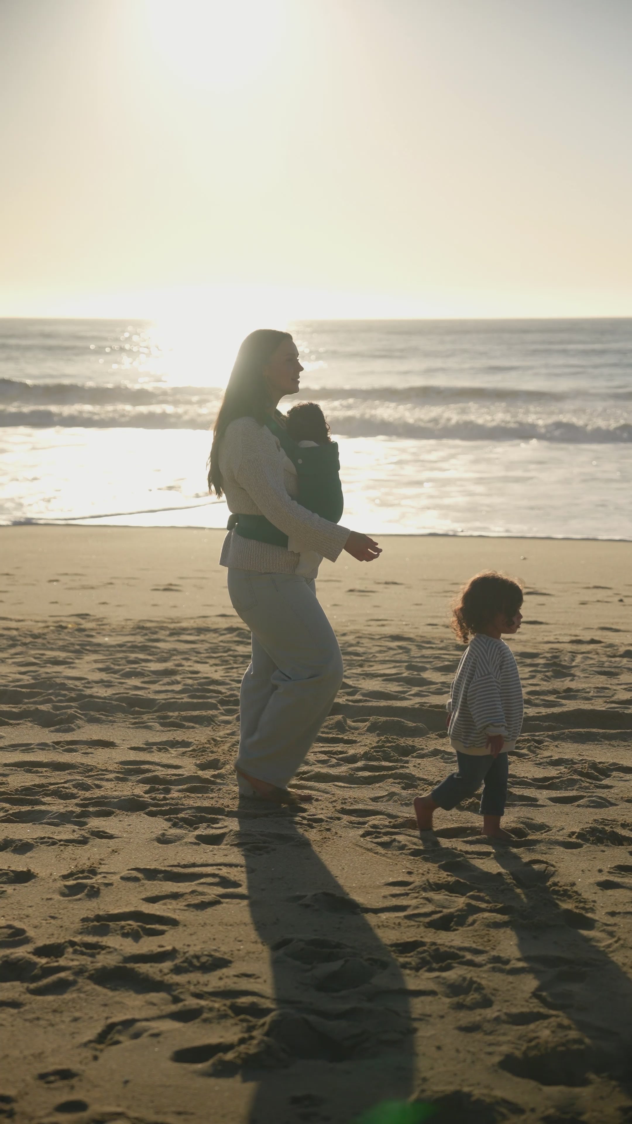 Thirty-second video showing scenes of men and women doing daily activities wearing Mabē buckle carriers and toddler slings: woman walking and playing at the beach with a toddler while carrying a baby, a couple strolling through a park while the man carries the baby, playing with toys in the house with a toddler with baby in the carrier, working out on a mat with baby in a carrier, flying kites, picnicking, making breakfast, and more beach time. The video concludes with a large MABĒ wordmark at the top.
