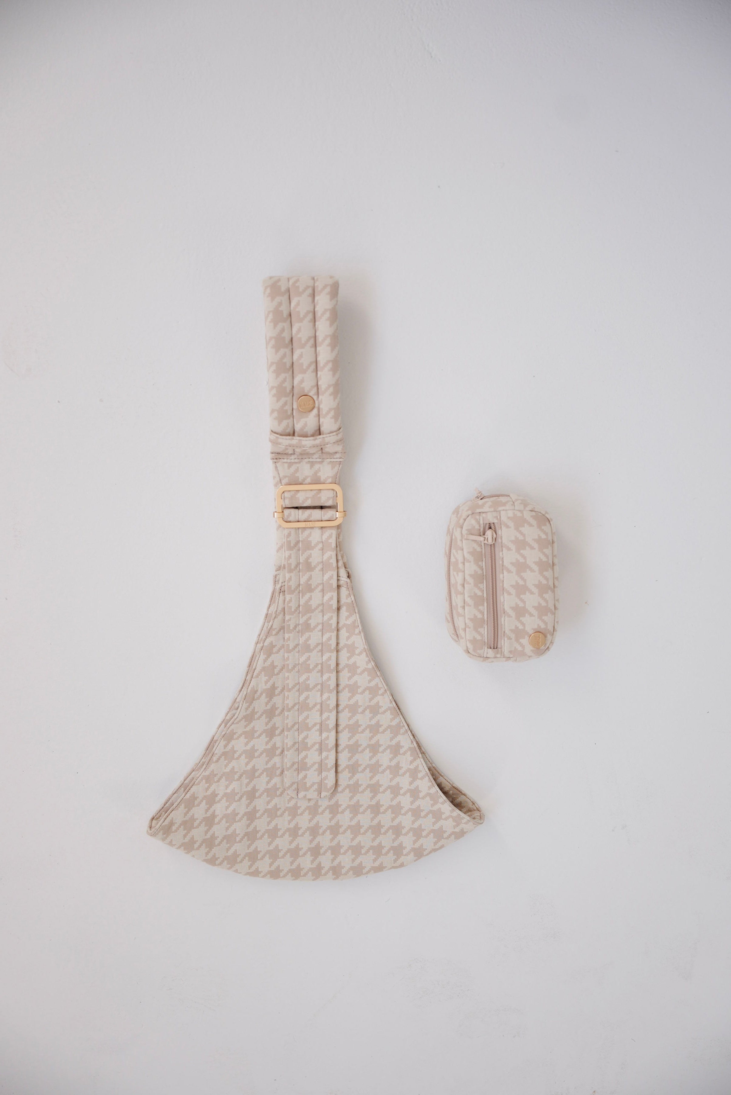 Beige houndstooth patterned Mabē toddler sling with a matching accessory bag on a white background