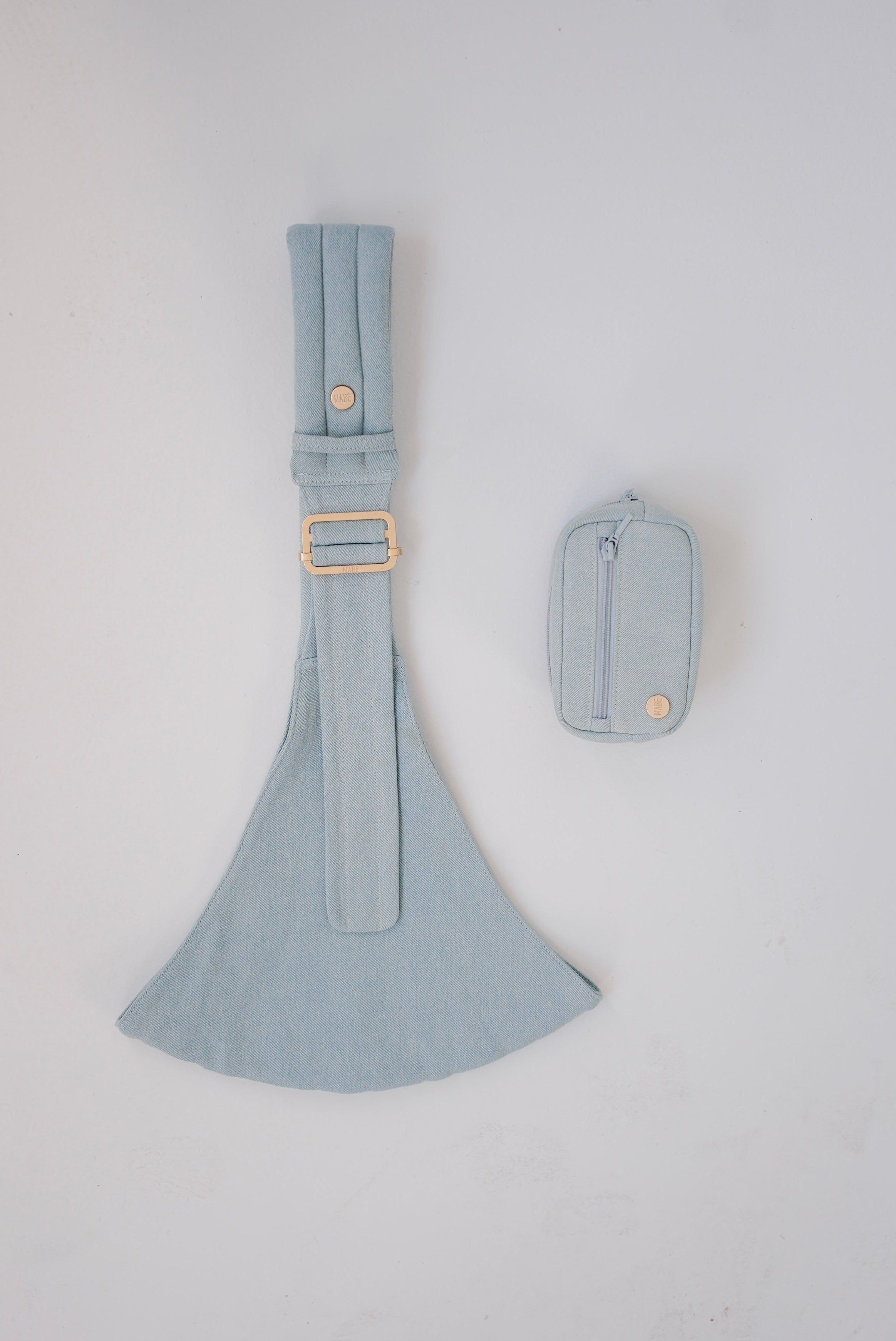 Light blue denim Mabē toddler sling with a matching accessory bag on a white background