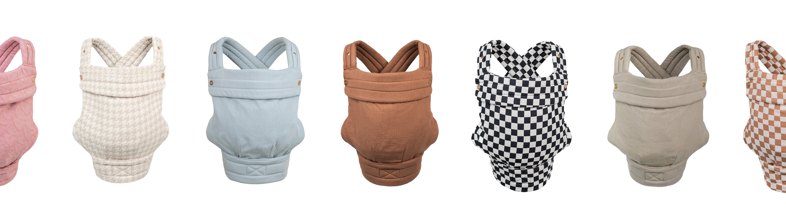 A row of seven Mabē buckle carriers is displayed against a white background, each shown from the front. The carriers come in a range of colors and patterns, including pink butterfly wings, beige and cream houndstooth, light blue denim, warm pinkish brown mocha, black‑and‑white checkered, beige-ish sage, and mocha checkered. All feature padded straps and structured fabric bodies, highlighting different styles and textures in a clean, uniform layout.
